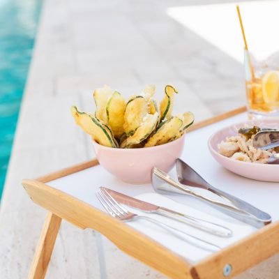 A selective closeup shot of a wooden tray filled with food, silverware and drinking glass